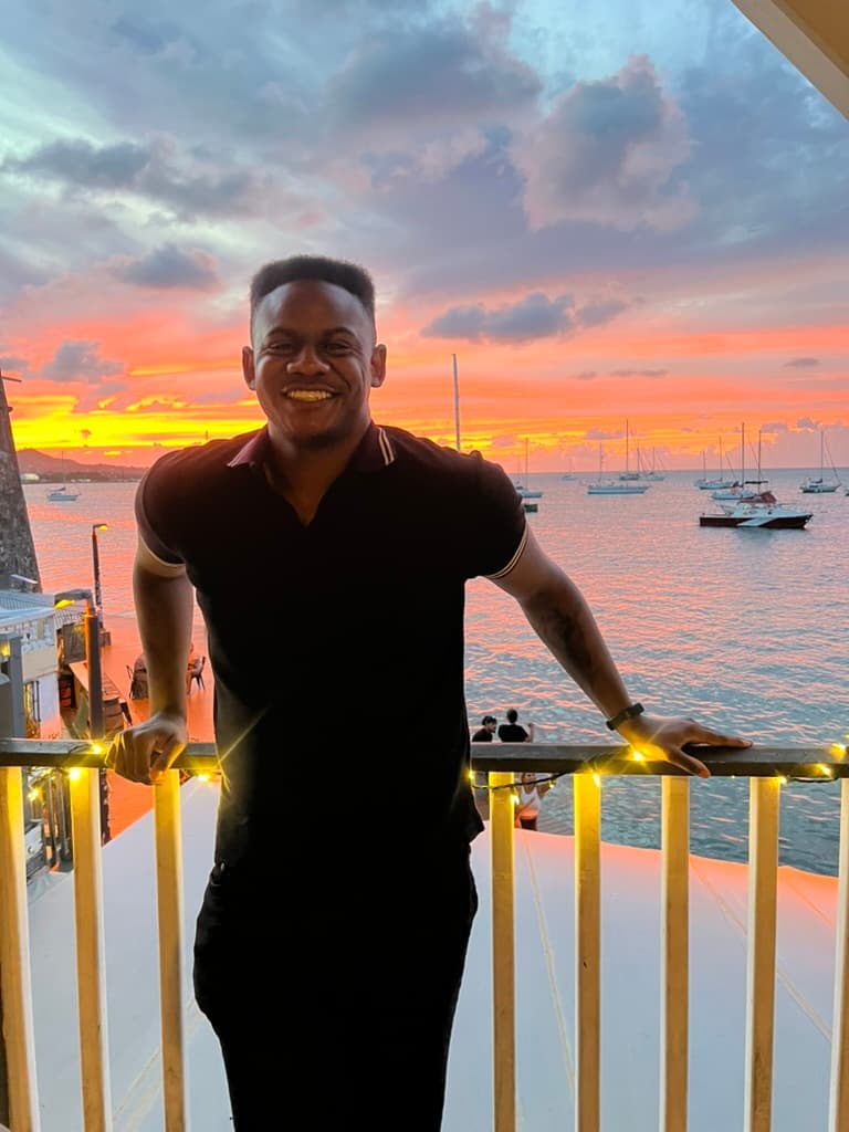 Jordan Bailey leaning on a railing at sunset overlooking the water.