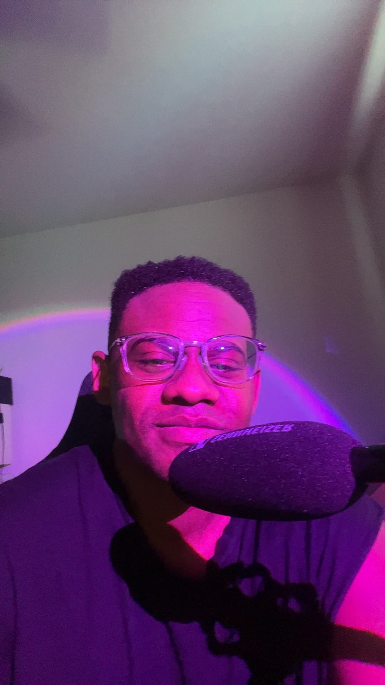Jordan Bailey lit in purple beside a microphone.